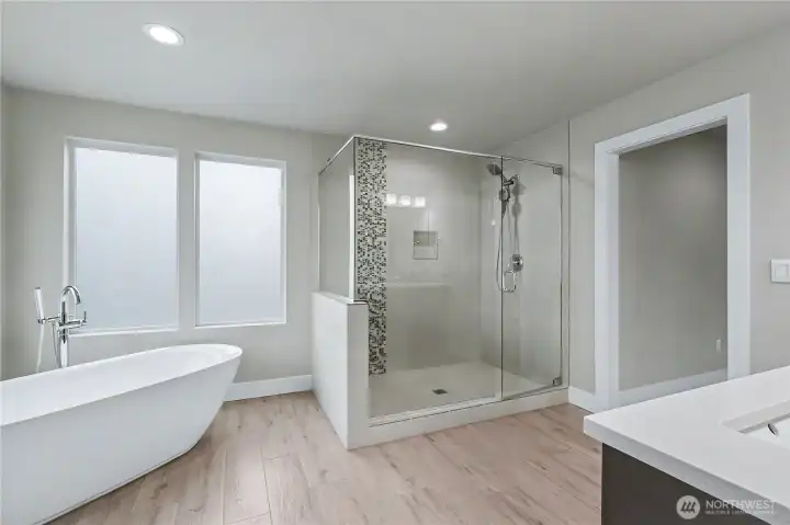 Primary bath view showing the soaking tub and shower, windows frosted for your privacy.