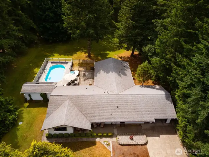 Looking down on the home and the pool surrounded by evergreens, in the middle of 2.39 acres.