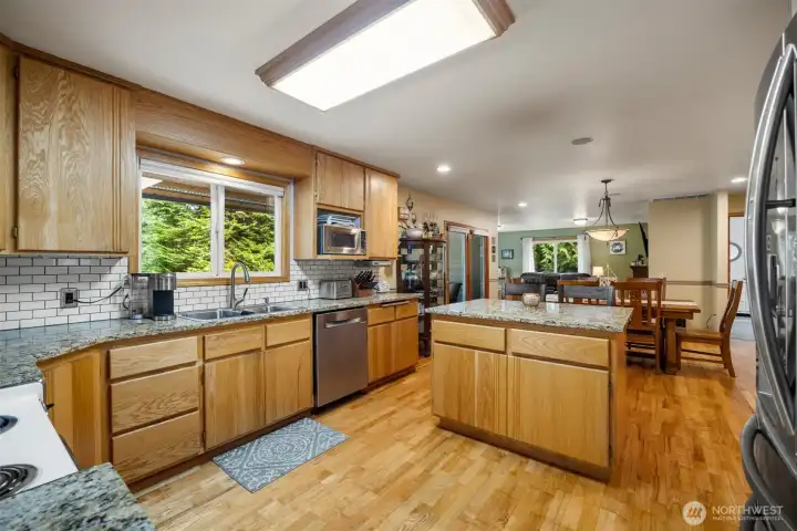 Welcome into the spacious kitchen with solid oak cabinets and slab granite counters and an island with an eating bar.