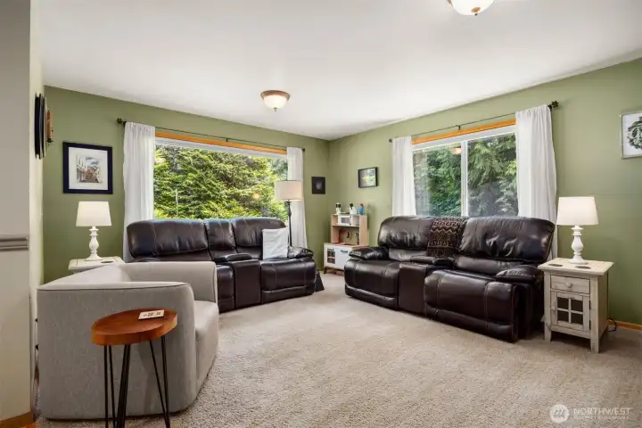 Another view of the spacious living room that looks out to the surrounding evergreen forest beyond the yard.