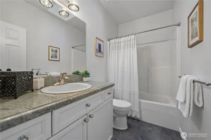 The full hall bath features a skylight, CoreTec flooring, granite countertops, and tasteful finishes.