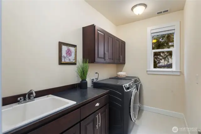 Upper level laundry room with side-by-side washer and dryer, utility sink and plenty of storage.