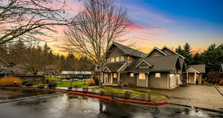 Peaceful corner setting at dusk with mature landscaping and a welcoming covered entry. Beautiful curb appeal in a quiet, well kept community.