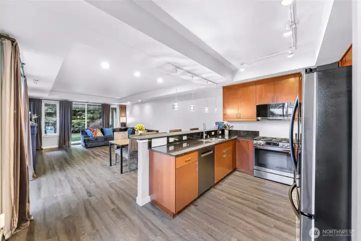 Spacious open concept living, dining, and kitchen area with large windows and views of the landscaped grounds.