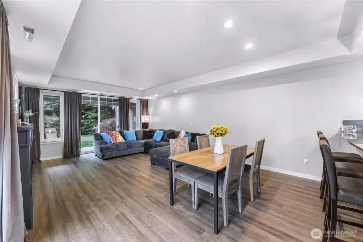 Spacious great room with large windows and sliding doors that bring in natural light and private green space views.