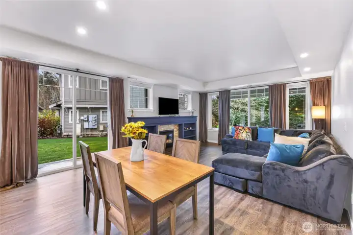 Light filled living and dining area with a cozy gas fireplace and easy access to the grassy backyard.