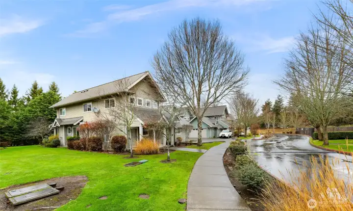 A wide, tree lined street leads you into this serene neighborhood with lush green space and sidewalks throughout.