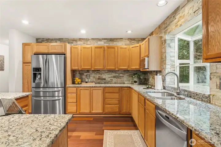 The kitchen is stylishly finished with full-height stone walls, slab countertops, and sleek stainless appliances.