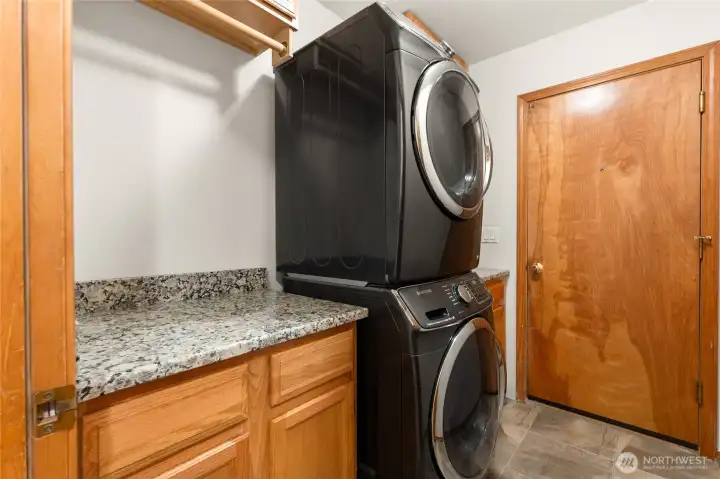 Efficient laundry and mudroom equipped with full-size front-load washer, dryer, and generous cabinet storage.