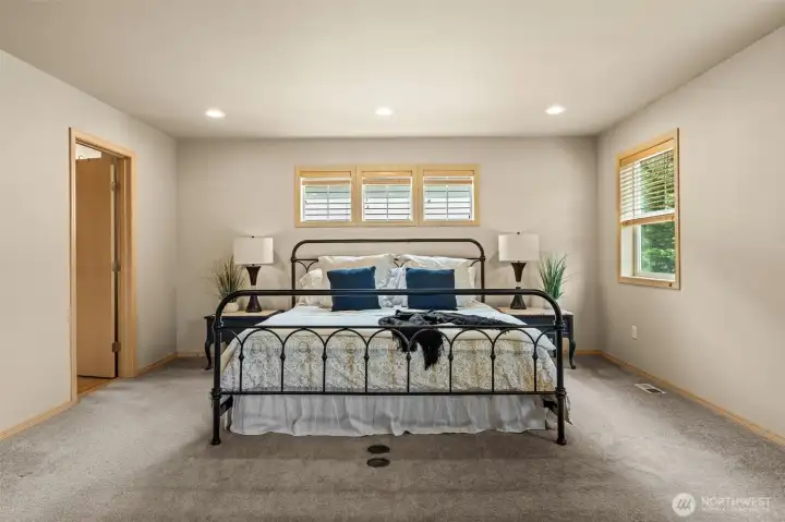 A true private retreat. This oversized primary suite offers a serene escape, characterized by soft natural light and plenty of room for a king-sized setup
