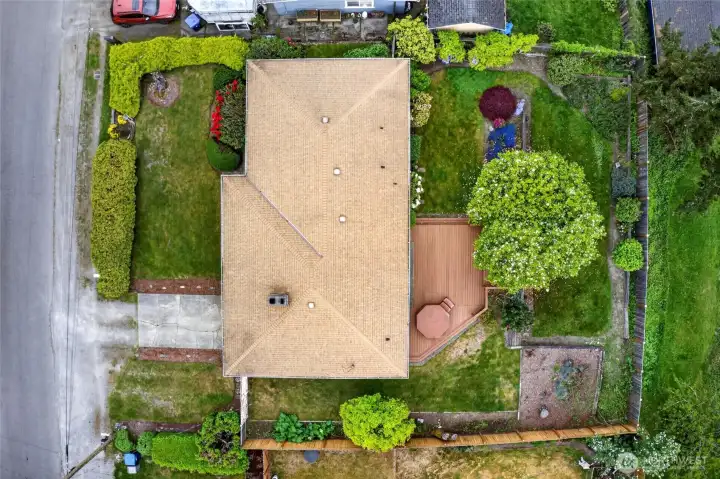 Expansive aerial view highlights the full property, including the oversized back deck, generous fenced yard, and mature trees that provide shade and privacy. There is ample space for gardening, pets, and play, plus room to add your own outdoor touches over time.