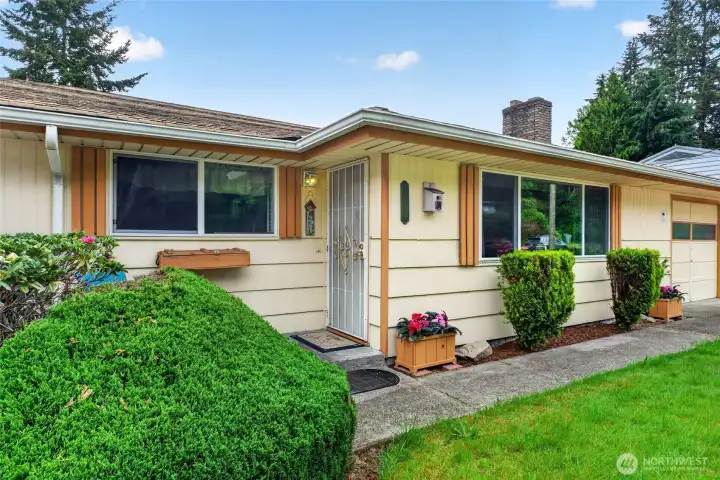 Charming front entry welcomes you home with a classic rambler façade, mature landscaping, and colorful flower boxes that hint at the home’s warm, lived-in character. A covered front stoop and screen door make everyday comings and goings easy in every season.