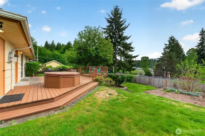 Expansive backyard deck with hot tub and terraced yard space, perfect for relaxing, entertaining, and enjoying the peaceful setting