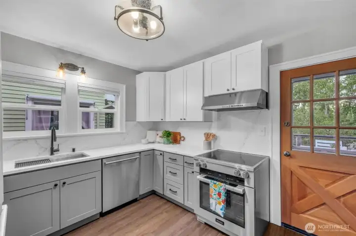 The kitchen features Quartz counters and backsplash, undermount sink, stainless steel appliances, Shaker cabinetry and door to deck