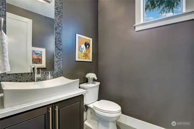 Powder room with vessel sink and decorative mosaic accent wall from sink counter to ceiling. Accent painted walls add warmth and drama.