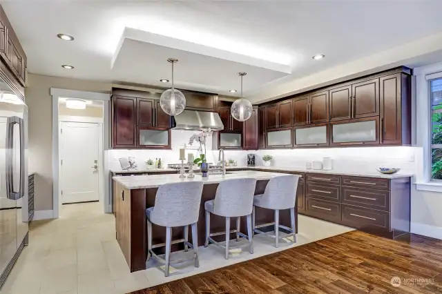 Spacious kitchen with dramatic drop ceiling accent over the island. Upgraded lighting fixtures throughout the home. Stone floors from garage door into mudroom, pantry, and kitchen.