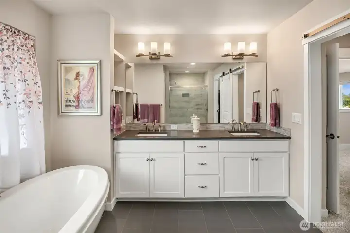 Double sink vanity and space-saving sliding door between bedroom area and bath.