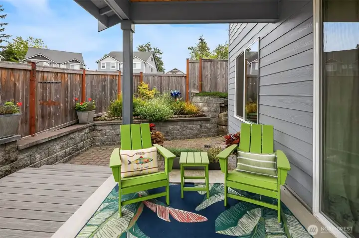 Private patio with a covered space, engineered decking, rock wall and patio pavers.