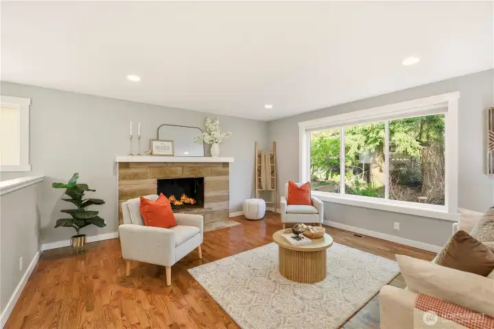 The open concept living area enjoys a lovely view over the wooded front yard and boasts refinished hardwoods, a wood burning fireplace and dimmable "smart" lighting that can be controlled via phone.