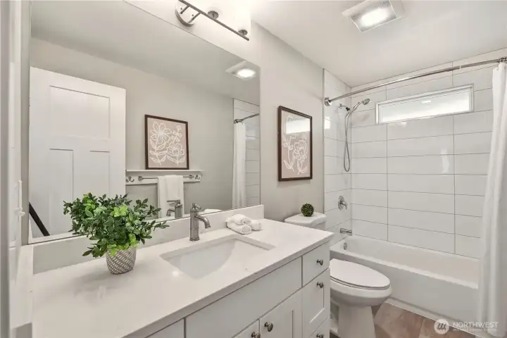 The main floor full bathroom is completely remodeled with Quartz countertop, undermount sink, soft close cabinets and drawers, new fixtures and tiled tub surround.