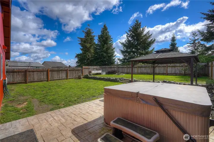 Private backyard retreat featuring a hot tub, gazebo, and open space-perfect for relaxing evenings, weekend gatherings, and everyday enjoyment.