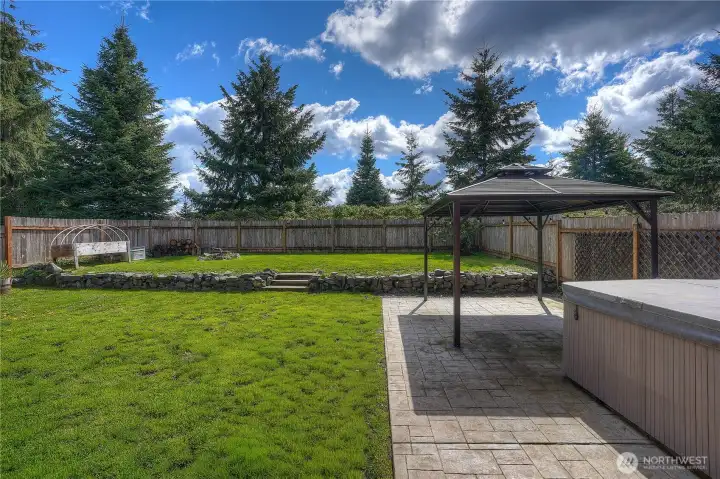 Fully fenced backyard featuring a hot tub, gazebo, and plenty of usable space for outdoor living and entertaining.
