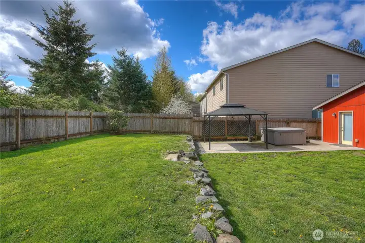 Designed for everyday living-this backyard offers space to garden, play yard games, gather under the gazebo, and unwind in the hot tub.
