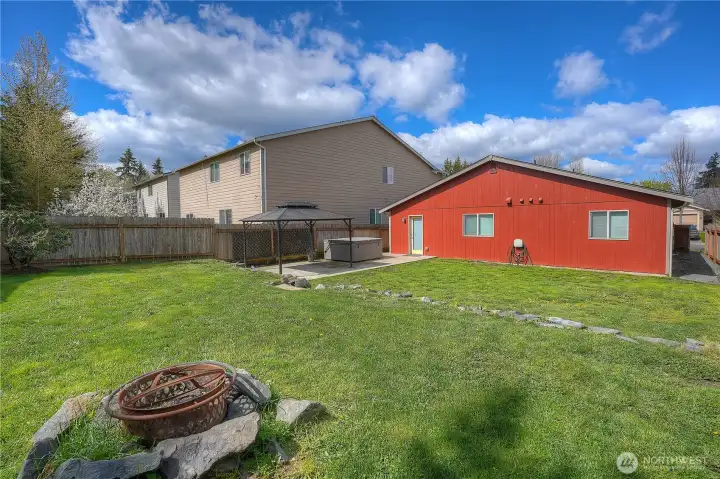 Spacious backyard with open green space and a fire pit