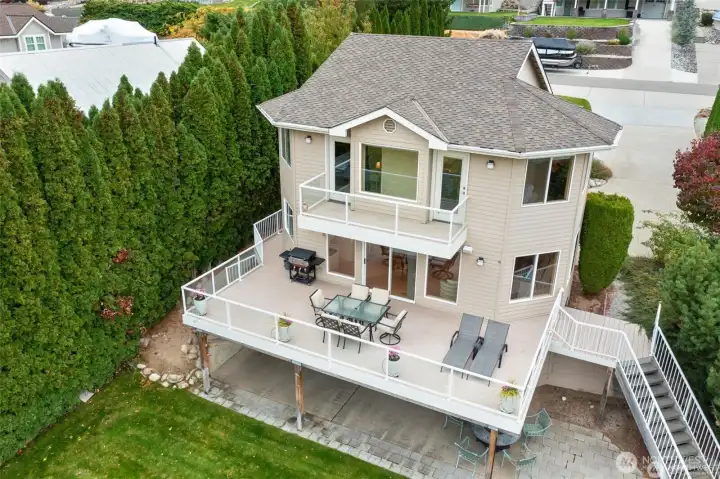 Elevated aerial perspective showcases expansive entertaining decks, multiple outdoor living areas, and prime waterfront positioning.