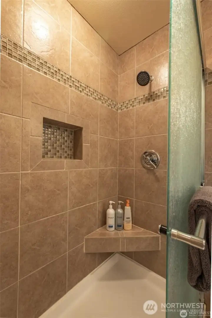 Custom tiled walk-in shower with built-in niche and elegant finishes creates a spa-like experience within the primary suite.
