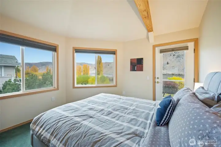 Spacious upper bedroom with soaring ceilings, natural light, and serene water views creates a relaxing private escape.