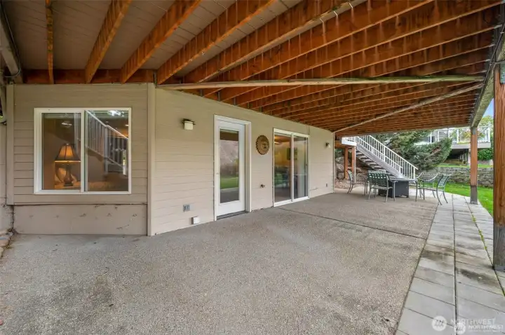 Lower patio and covered entertaining space extend the home’s living area outdoors while overlooking the lush waterfront lawn.