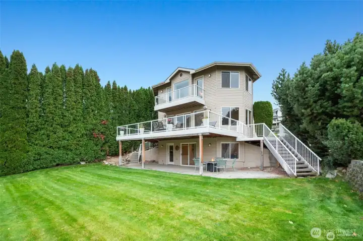 Manicured lawn stretches from the home toward the waterfront, offering a beautiful setting for outdoor gatherings and recreation.