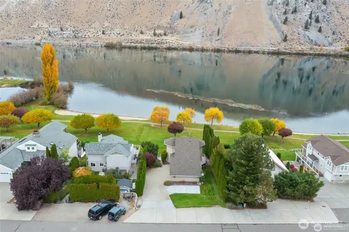 Aerial view from the street highlights the home’s attractive curb appeal, privacy landscaping, and desirable waterfront community location.