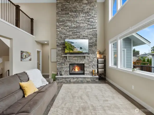 Spectacular Great Room with soaring ceiling, floor-to-ceiling stone fireplace & partial views.