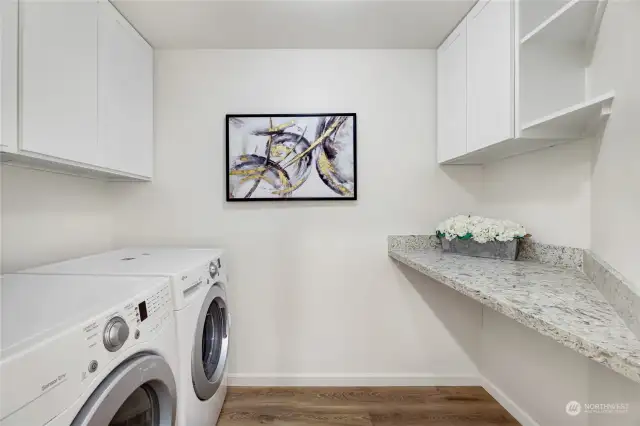 This large laundry room offers a Quartz folding table, and additional storage in the built-in cabinets.