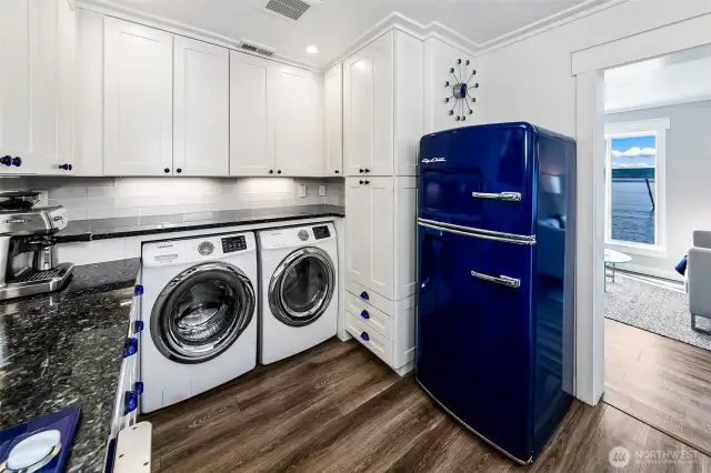 Behind the scenes, style meets utility with integrated laundry, abundant cabinetry, and a vintage-inspired fridge—all framed by granite counters and a peekaboo view of the Sound.