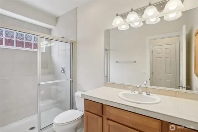 Primary bathroom with tile shower and window above shower provides abundance of natural light.