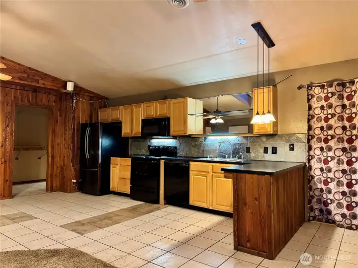 Full second kitchen in the walkout basement featuring ample cabinetry, full appliance package, tile flooring, and a large peninsula with pendant lighting. Open to a spacious living area, this level offers excellent flexibility for multigenerational living, guests, or extended living space.