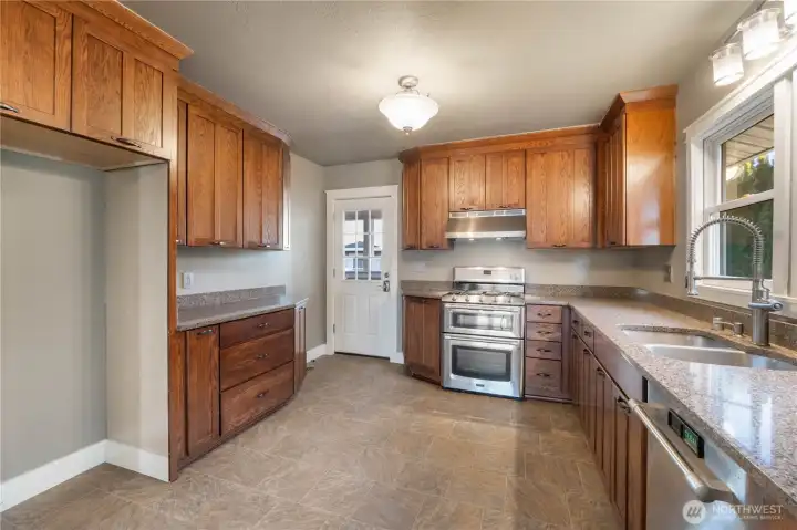 Stainless appliances, granite counter surfaces and rich wood cabinetry.