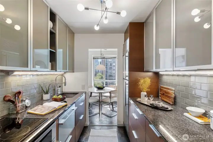 Granite counters and subway tile backsplash in neutral earthy tones makes the space desirable to work in, with lots of under-cabinet lighting.