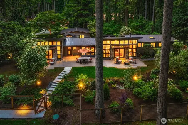 Professionally landscaped grounds with exterior lighting, in-ground sprinklers, fencing and mature foliage