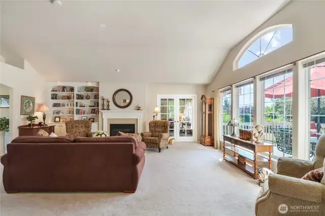 Bright living room with wall of windows looking out to the   beautiful landscaped yard complete with rose garden