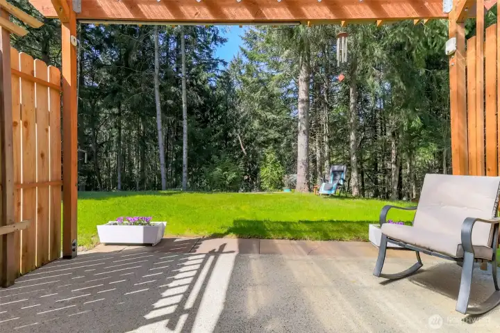 Who wouldn't want to relax on this covered patio overlooking this serene backyard?