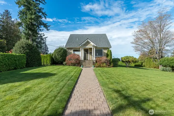 Sprawling lawn with mature landscaping and privacy hedges