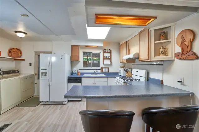 Kitchen with laminate wood flooring and lots of counter space. Utility room with door to garage.