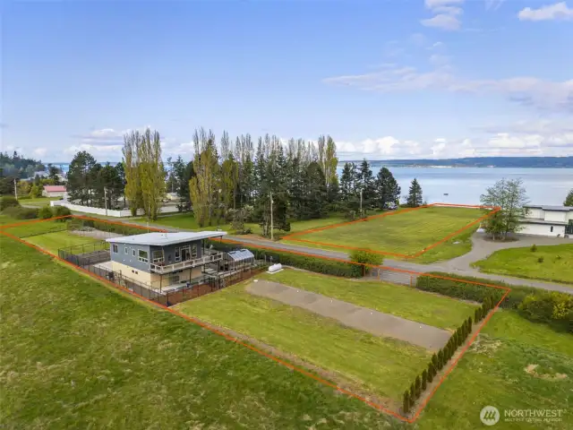 Elevated view of the sleek modern home, surrounded by open fields and just moments from sparkling shoreline vistas.