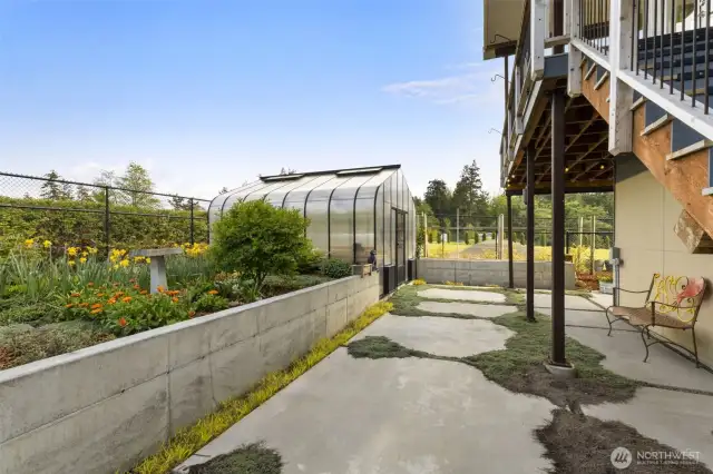 Serene garden walkway with vibrant plantings and access to the greenhouse.