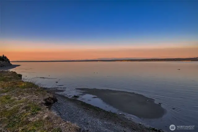 Sunset over the water casts vibrant colors across the sky and bay.