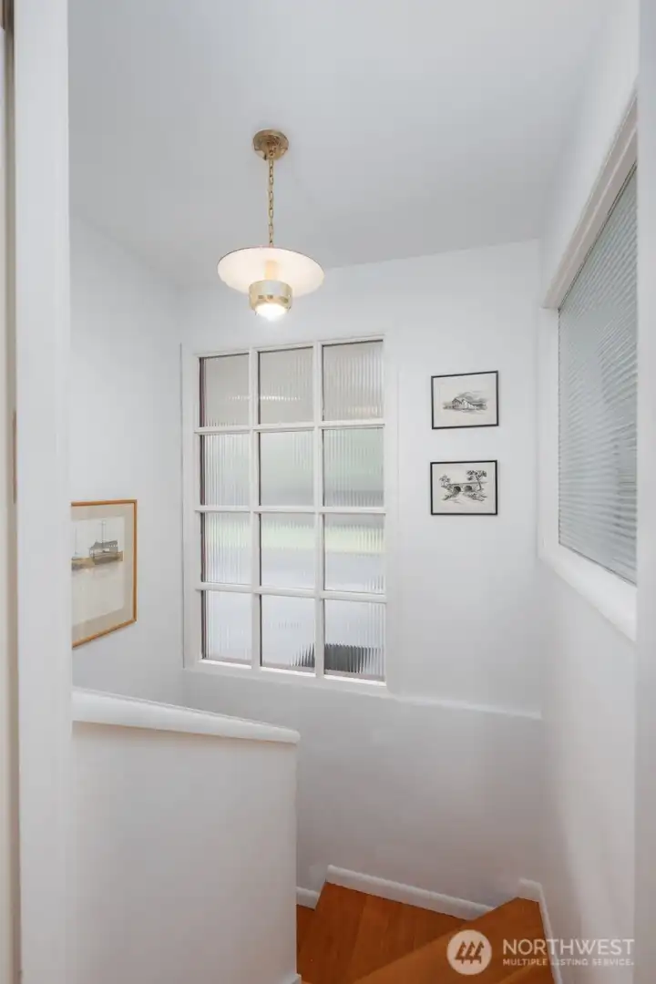 Stairwell to lower level is light filled and has original fir stair treads.